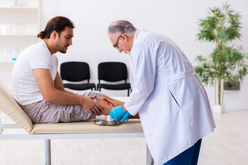 Obraz premium Leg injured man visiting old doctor in first aid concept