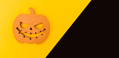 Halloween background idea.Flat lay wooden Jack o lantern spooky pumpkin on black yellow paper color background.Halloween design with copy space for text advertising.Background idea in Autumn October.