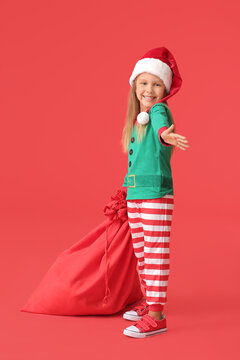 Cute little girl dressed as elf and with Santa Claus bag on color background