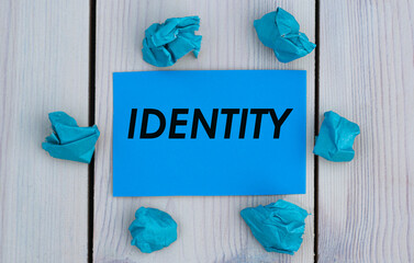 IDENTITY - word on blue paper on a light background with crumpled pieces of paper
