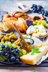 Cheese plate served with fruits, honey and snacks, close up. Assorted cheese background.