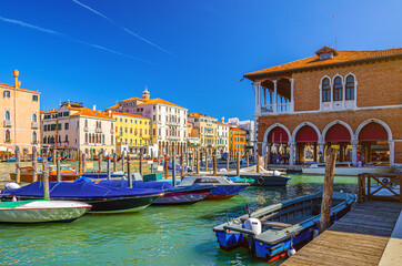 Boats moored in wooden pier dock of Grand Canal waterway in Venice historical city centre with Rialto Mercato, row of colorful buildings Venetian architecture. Veneto Region, Northern Italy. - obrazy, fototapety, plakaty