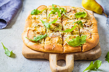 Homemade pizza with pear,  arugula and cheese, gray background.