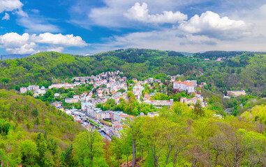 Fototapeta na wymiar Karlovy Vary city aerial panoramic view with row of colorful multicolored buildings and spa hotels in historical city centre. Panorama of Karlsbad town and Slavkov Forest mountains, Czech Republic