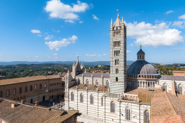 Top view of the roof, tower, dome and square in front of the meieval church Siena Cathedral (Duomo di Siena) of the 13th century in Siena, Italy