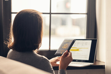 Woman  holding passport filling visa application form on the laptop. Online and home work concept.