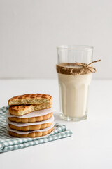 Cookies and a glass of milk close up on a linen napkin on a white background