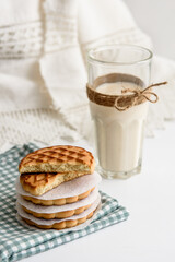 Cookies and a glass of milk close up on a linen napkin on a white background