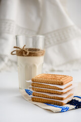 Cookies and a glass of milk close up on a linen napkin on a white background
