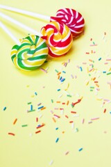 Colorful lollipops and confetti on yellow background. Sweets for party. Sugar