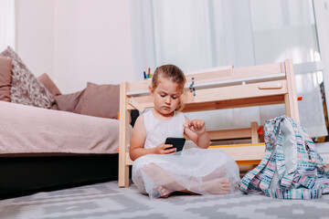 Little student at home after school. Back to school. Little girl studies at home. School student with smartphone.