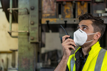 Technical supervisor wearing a mask is operating a crew through a radio communication in the...