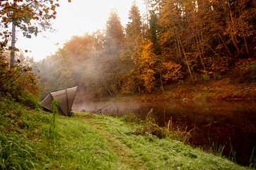 Autumn, fishing in the river with a tent and fishing rods