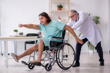 Naklejka premium Young male patient in wheel-chair and experienced doctor traumatologist