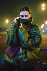 Woman in trendy green jacket in blue light
