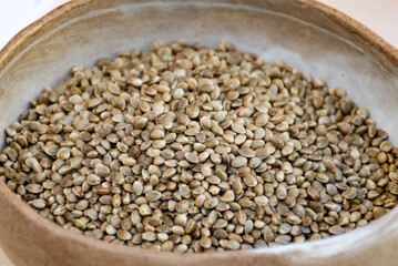 Dry hemp cannabis seeds in a ceramic bowl, close up