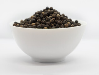 Black pepper, herbs, spices in a white bowl.