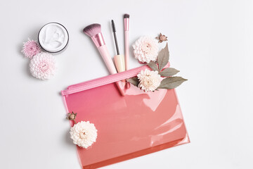 beauty routine concept. a pink cosmetic bag, makeup brushes, mascara, and a bottle of moisturizer. vintage tinting. top view