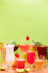 Summer drinks with fruit juice and ice. Refreshing summer beverages in different glasses over green background.