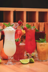 Summer drinks with fruit juice and ice. Refreshing summer beverages in different glasses over rustic wooden background