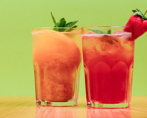 Summer drinks with fruit juice and ice. Refreshing summer beverages in different glasses over green background.