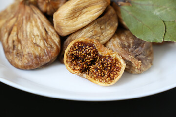 Dried figs in a white plate on a dark glass table