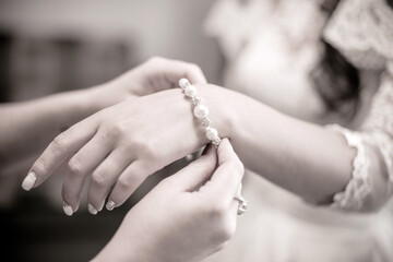 The girl puts a bracelet on the bride's hand