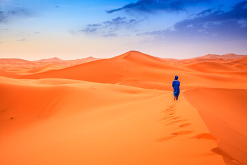 Fototapeta na wymiar Berber man walking across on desert dunes