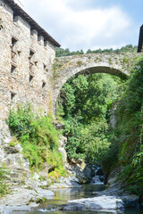 Fototapeta na wymiar BEGET, CATALONIA, SPAIN, EUROPE, SEPTEMBER 2020. Beautiful landscape of the medieval bridge surrounded by stone houses in the picturesque town of Beget, it is an important tourist place in Catalonia.