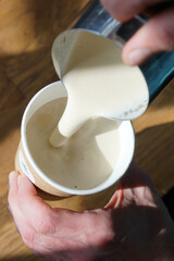 Barista prepares creamy coffee in paper cup