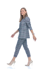 side view of young woman in blue checkered suit walking