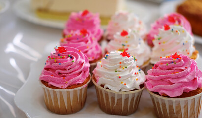 cakes in a basket with pink and white cream on the holiday table. Birthday, wedding