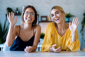 Smiling young woman looking and speaking through the webcam while making a video conference in her startup small business.