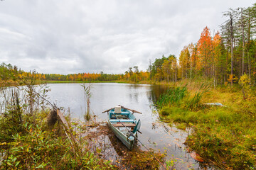 Lake in the Arkhangelsk region, northern Russia. A wooden boat on the shore of the lake. Cloudy autumn weather