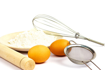 Rolling pin for dough, egg, flour, whisk, strainer on a white background. Dough preparation. Baking...