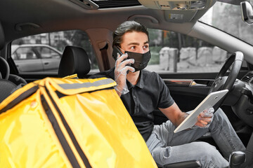 Obraz premium Smiling delivery man in protective mask delivered hot pizza from restaraunt to the customer