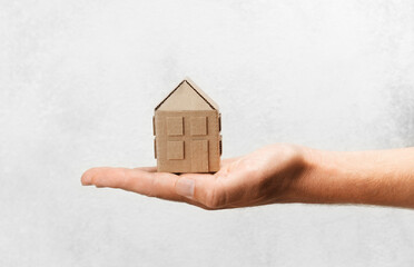 Hand holds house. Buying or selling home, real estate insurance. Protection and safety life.