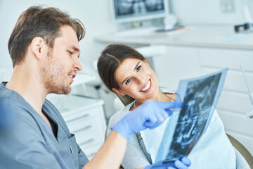 Male dentist and woman discussing x-ray results in dentist office