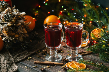 Fototapeta na wymiar glasses with mulled wine on a wooden table decorated with a Christmas trees. Traditional winter alcoholic drink with orange slices