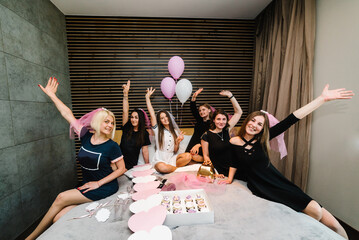 Bride and bridesmaids celebrating bachelorette party in bedroom. Happy girls with veil. Maiden...