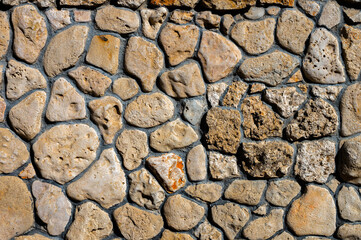 An uneven wall of decorative stacked cobblestones. Medieval background decorative insert