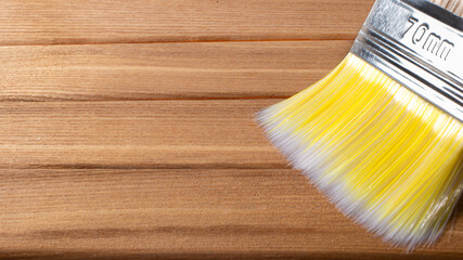 A paint brush on a wood brown background with a place for text to paint walls and objects with paint. Tools for repair.