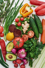 Top view of various colorful vegetables and herbs for making summer salad isolated over white background