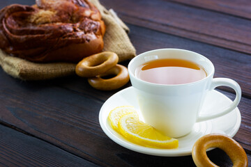 White cup of tea with lemon, bun, bagel and cookies. Lunch break at a coffee shop