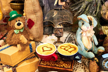 Two cups of cappuccino with drawings of hearts on a table among toys and New Year's decorations