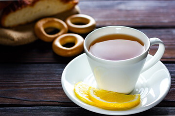 White cup of tea with lemon, bun, bagel and cookies. Lunch break at a coffee shop