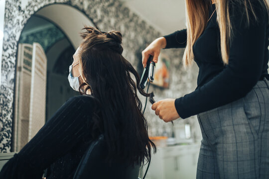 Woman in medical mask gets her hair done in beauty salon during pandemic