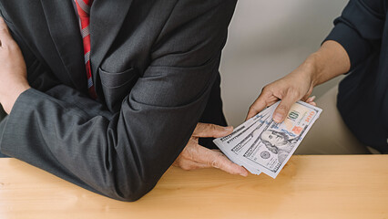 Businessman giving money while making deal to agreement a real estate contract and financial corporate.Bribery and corruption concept