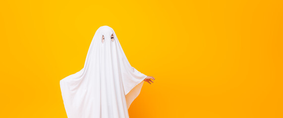Little kid wearing cute halloween ghost costume on yellow background - obrazy, fototapety, plakaty