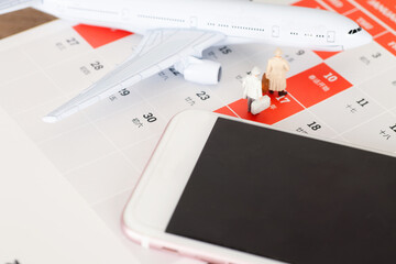 Small airplane model and mobile phone on desk calendar background